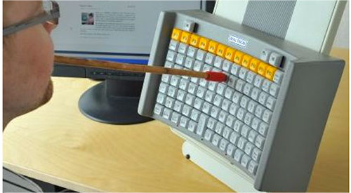 A person using a mouth stick to type on a vertical keyboard